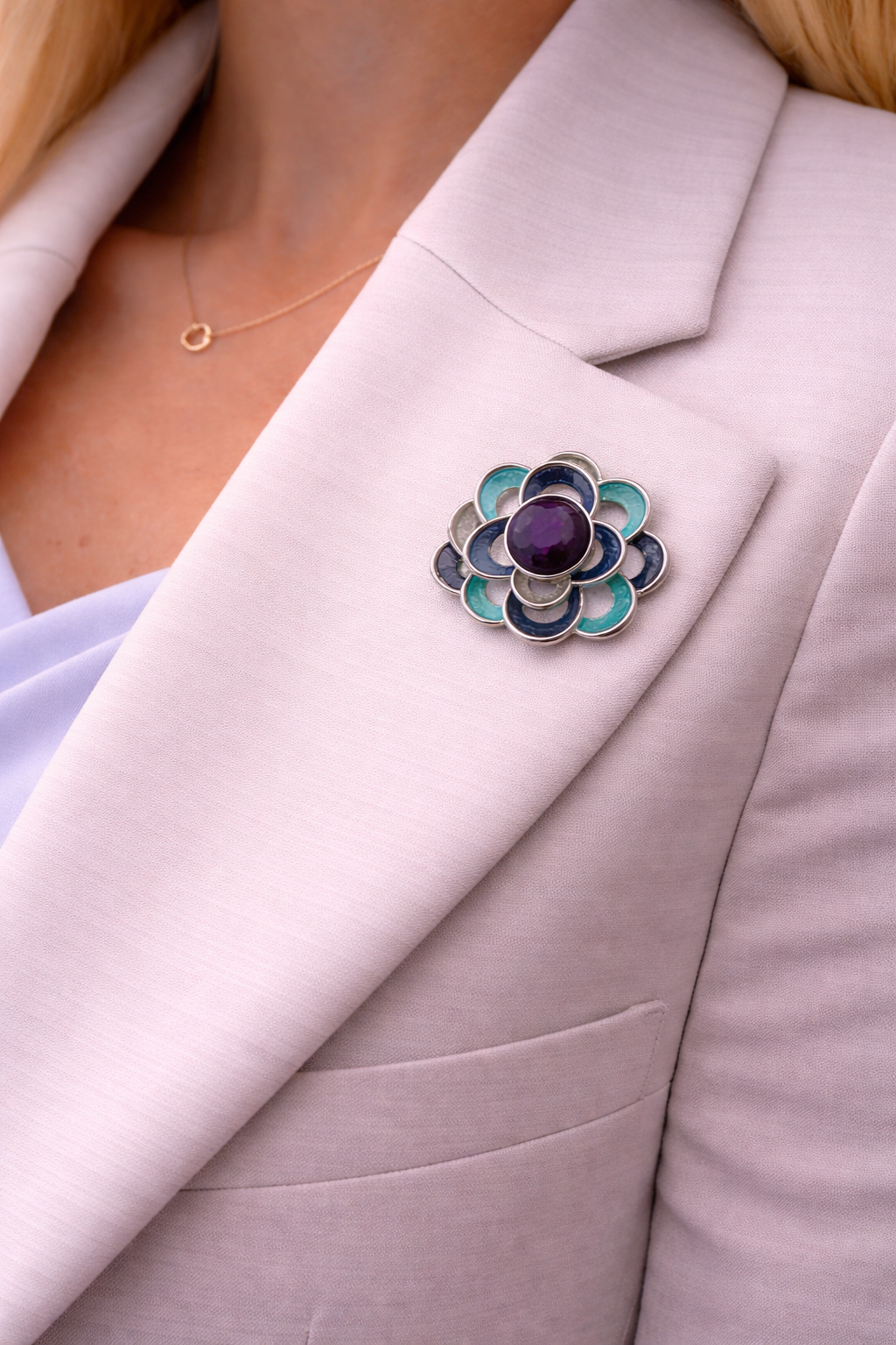 Magneetbroche Nr.48 Bloem Oceaanblauw gedragen op een licht colbert, elegante damesbroche in oceaanblauwe tinten met zilverkleurige details.