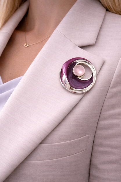 Magneetbroche Nr.50 Paarse Gloed gedragen op een licht colbert, elegante damesbroche in paarse tinten met zilverkleurige details.