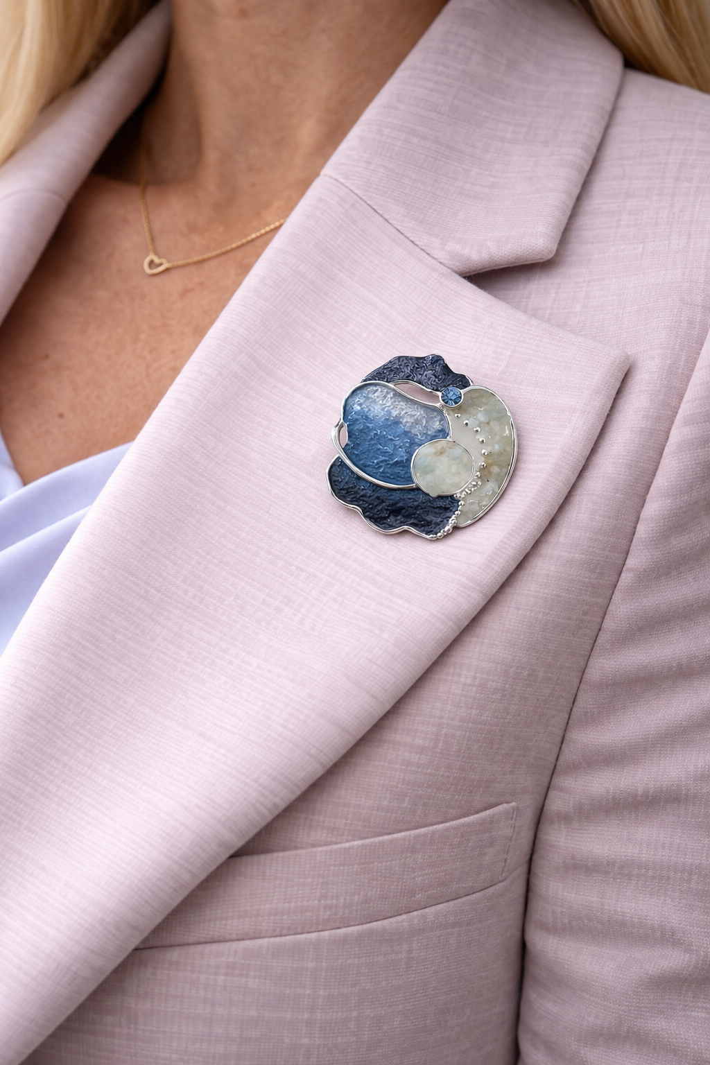 Magneetbroche Nr.52 Oceaan Blauw Harmonie gedragen op een licht colbert, elegante damesbroche met oceaanblauwe tinten en zilverkleurige details.