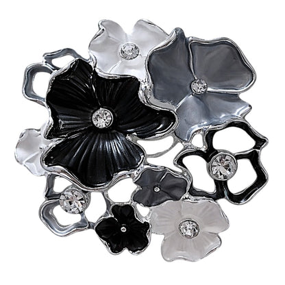 Zwart-witte magneetbroche met speelse bloemen, glanzende strassstenen en zilverkleurige details. Deze elegante broche zonder speld combineert contrast, verfijning en tijdloze klasse in één bijzonder sieraad.
