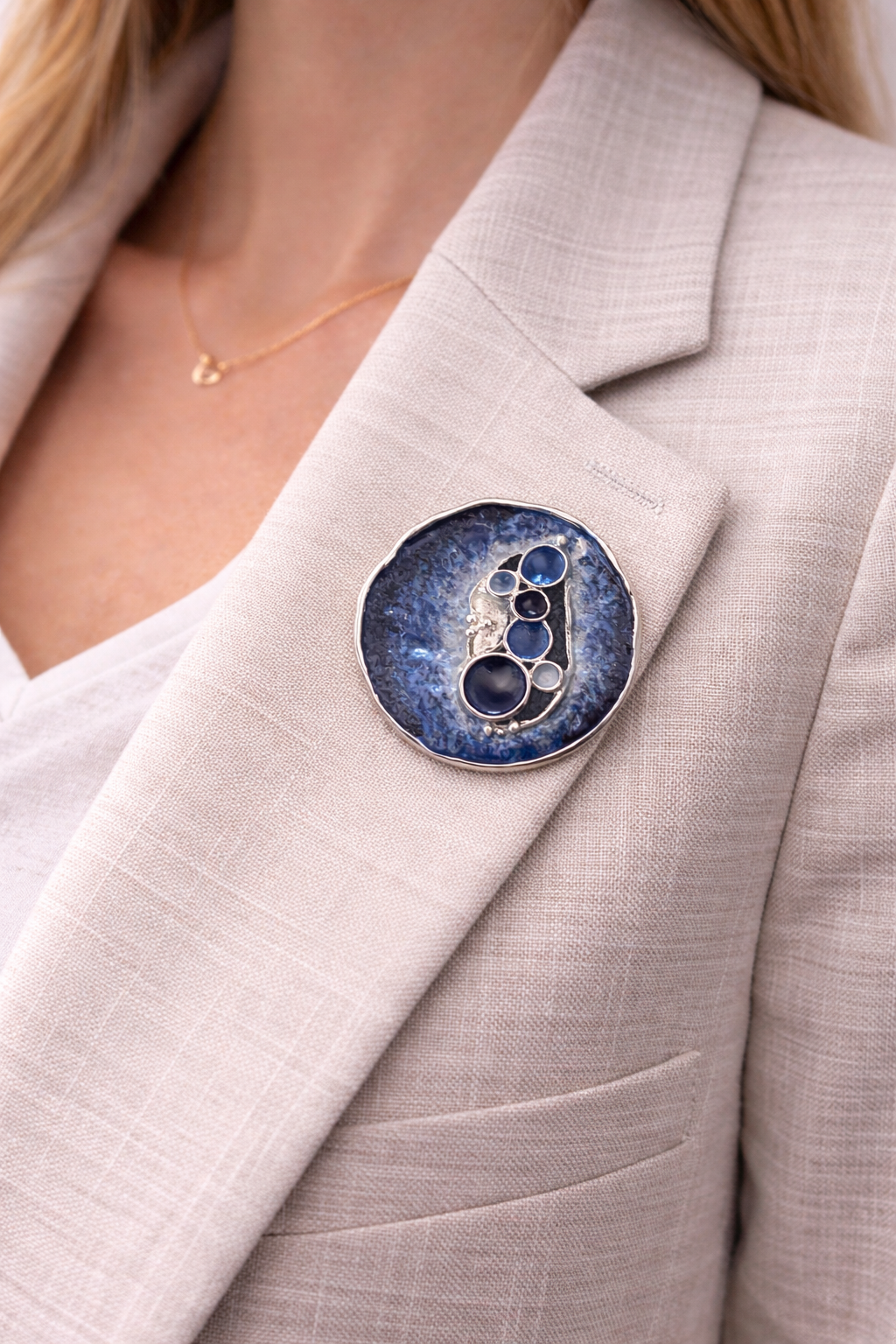 Magneetbroche Nr.71 Donkerblauwe Pracht gedragen op een licht colbert, elegante damesbroche met diepe blauwtinten en ronde details.