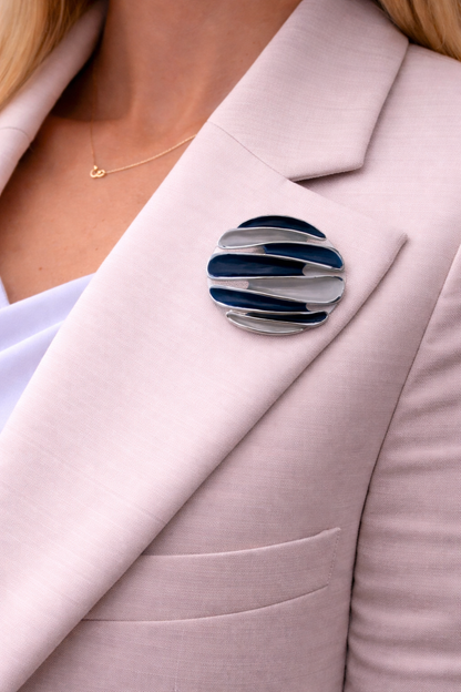 Magneetbroche Oceaan Harmonie gedragen op een licht colbert, lagen in diepblauw en zilver met moderne uitstraling