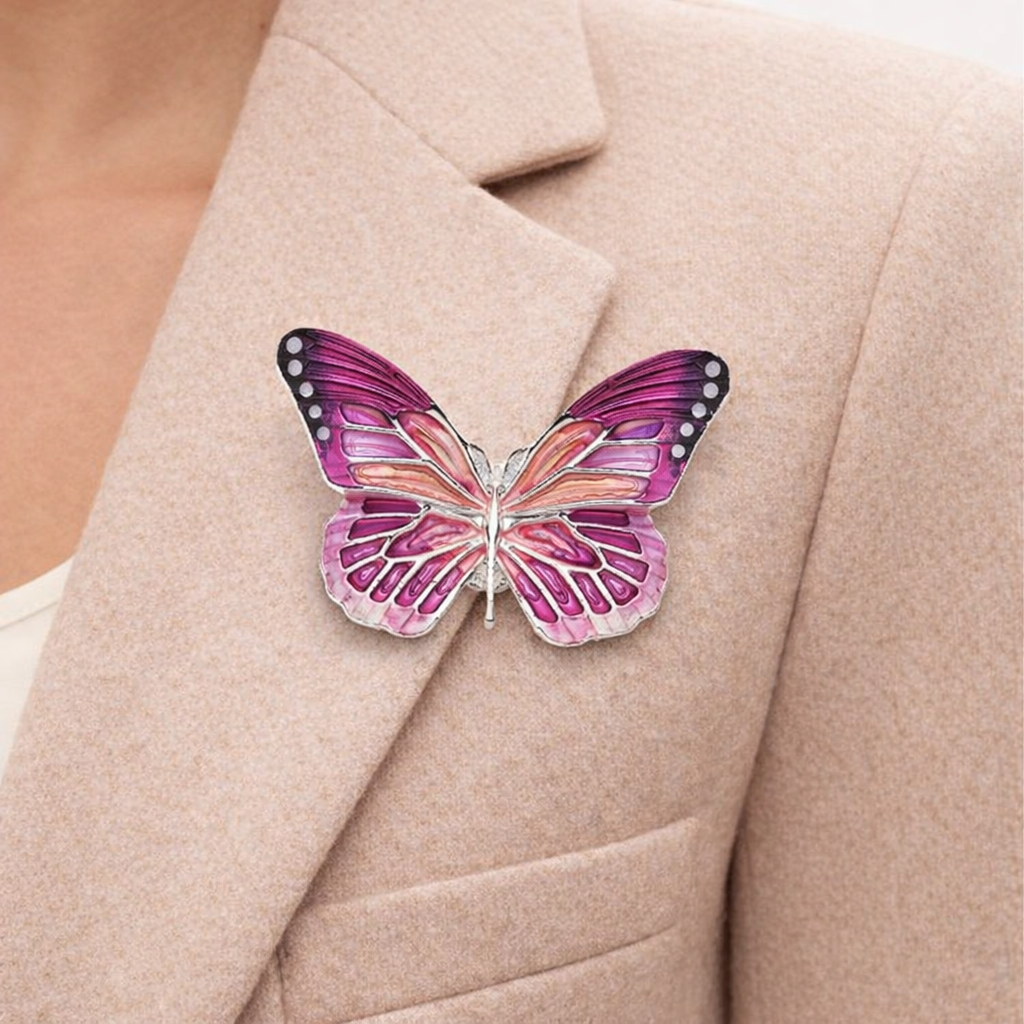 “Magneetbroche Roze Vlinder gedragen op een colbert, sierlijke vleugels in roze- en paarstinten met elegante details.”