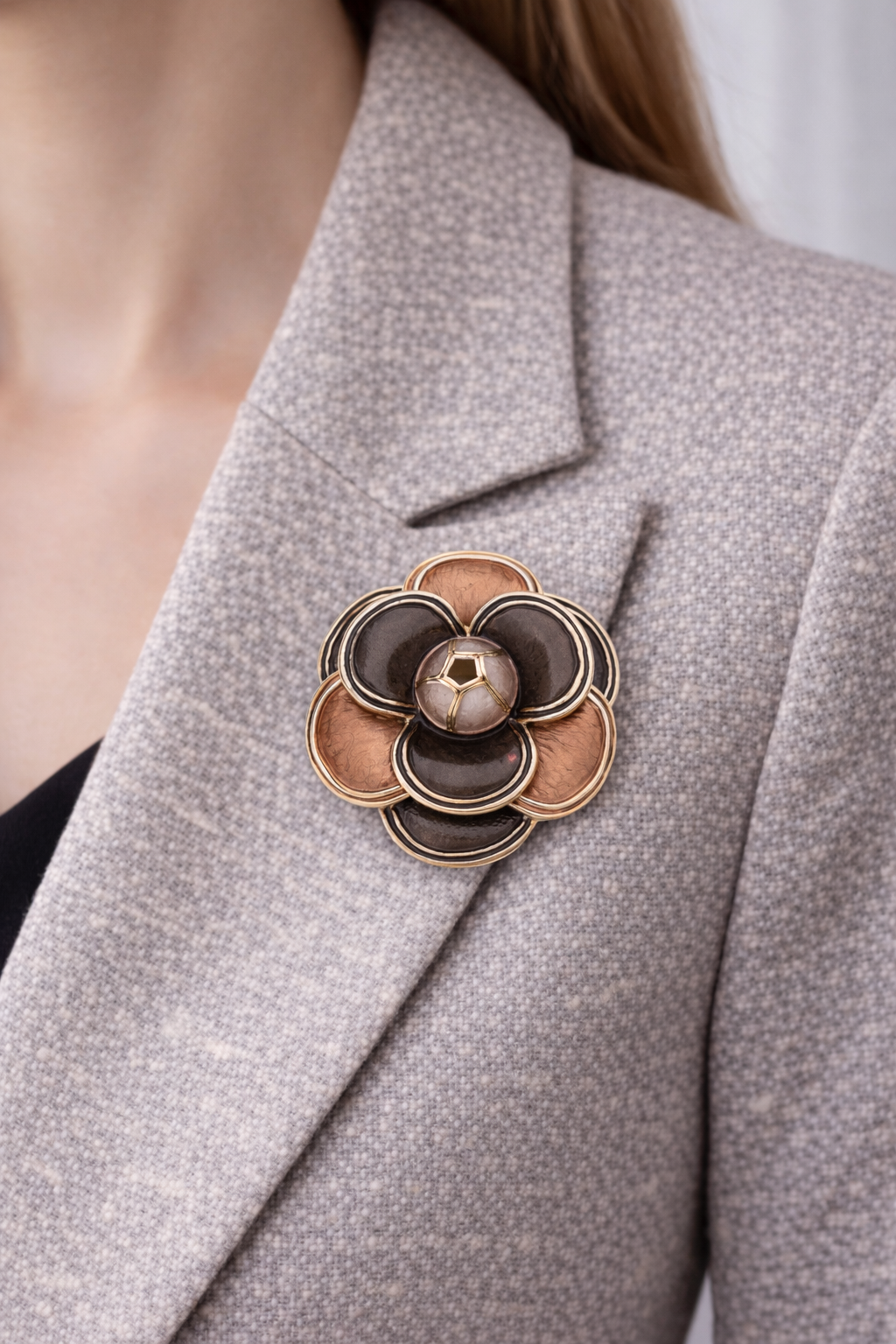 “Magneetbroche Zachte Gloed gedragen op een licht colbert, bloemvorm in warme bruin- en koperkleurige tinten.”