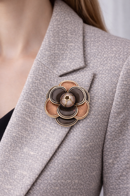“Magneetbroche Zachte Gloed gedragen op een licht colbert, bloemvorm in warme bruin- en koperkleurige tinten.”
