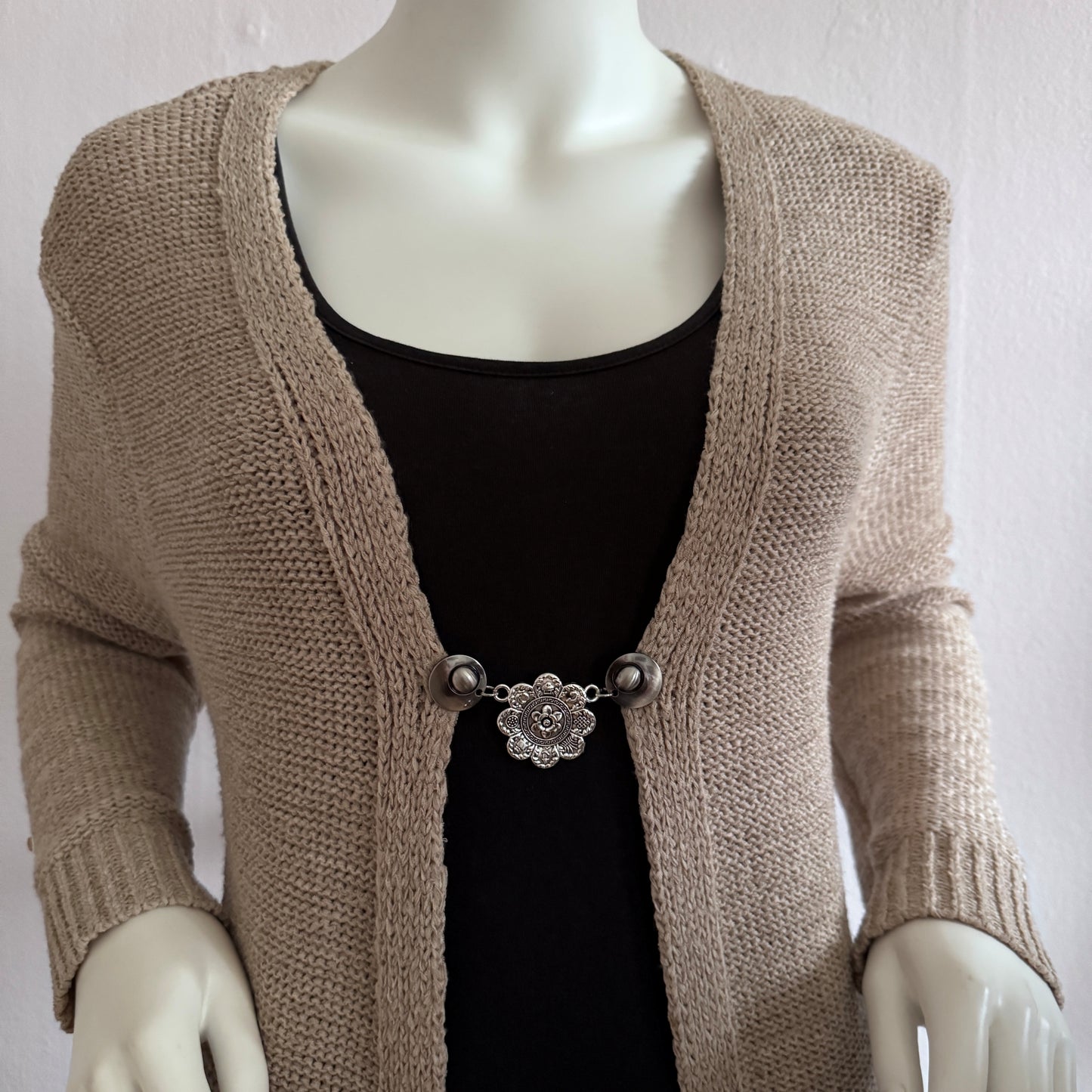 Vestsluiting De Acht Zegeningen gedragen op een beige gebreid vest, elegante Fashionclip met zilverkleurige clips en sierlijke mandala tussenbedel.