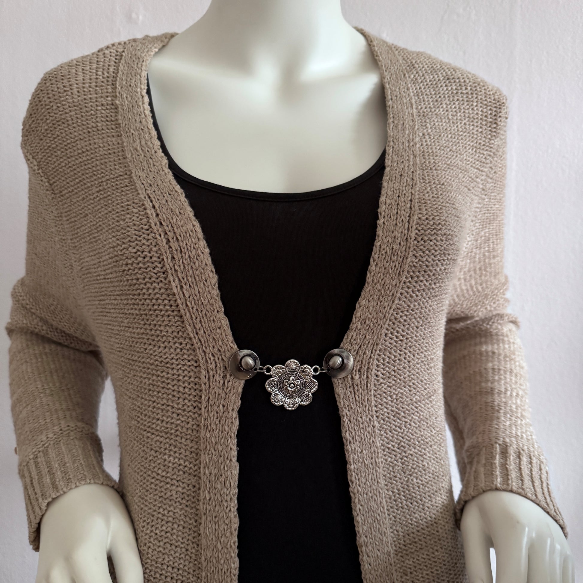Vestsluiting De Acht Zegeningen gedragen op een beige gebreid vest, elegante Fashionclip met zilverkleurige clips en sierlijke mandala tussenbedel.