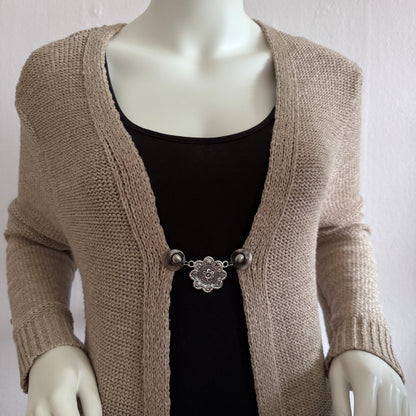Vestsluiting De Acht Zegeningen gedragen op een beige gebreid vest, elegante Fashionclip met zilverkleurige clips en sierlijke mandala tussenbedel.