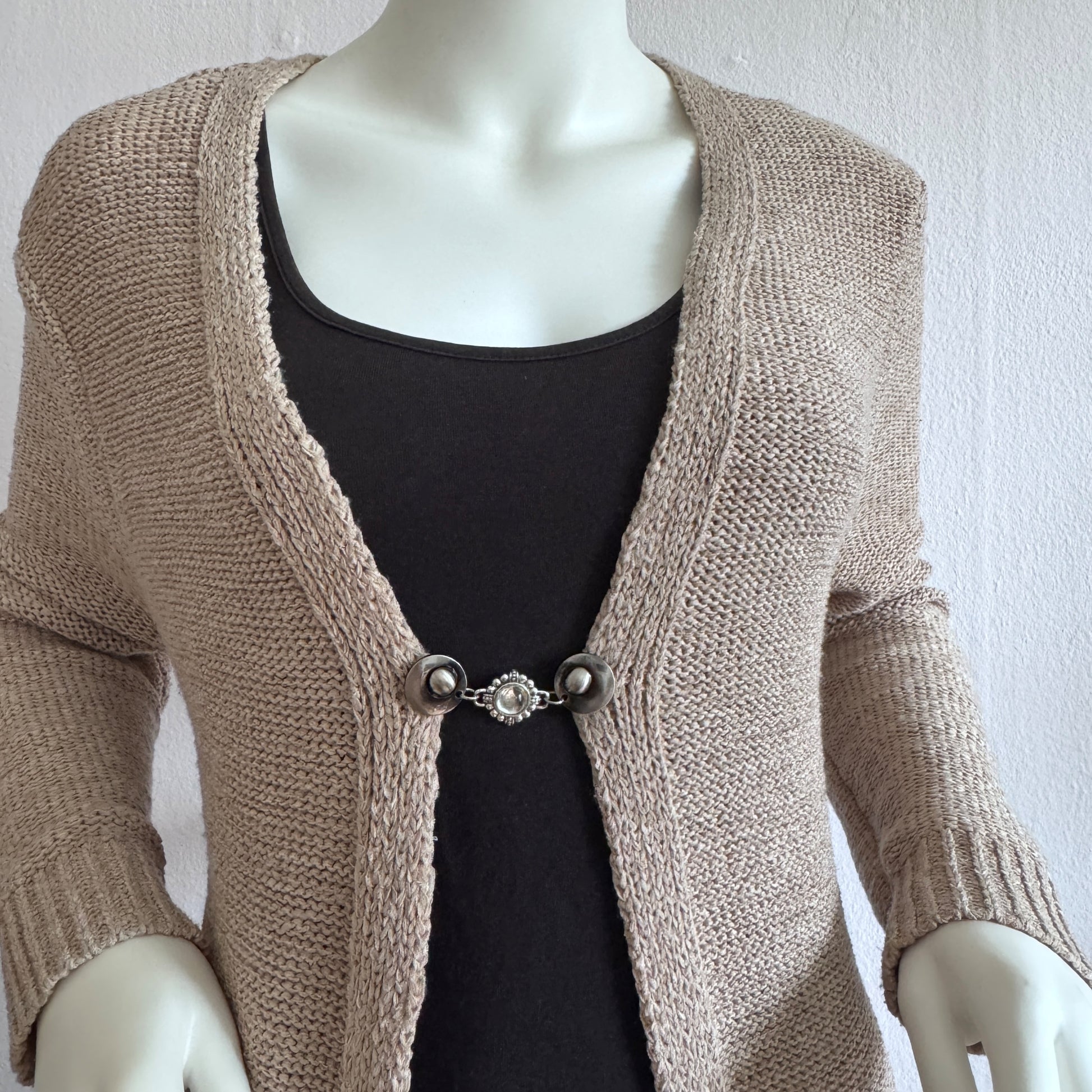 Vestsluiting De Kameleon gedragen op een beige gebreid vest, elegante Fashionclip met zilverkleurige clips en glinsterende siersteen tussenbedel.