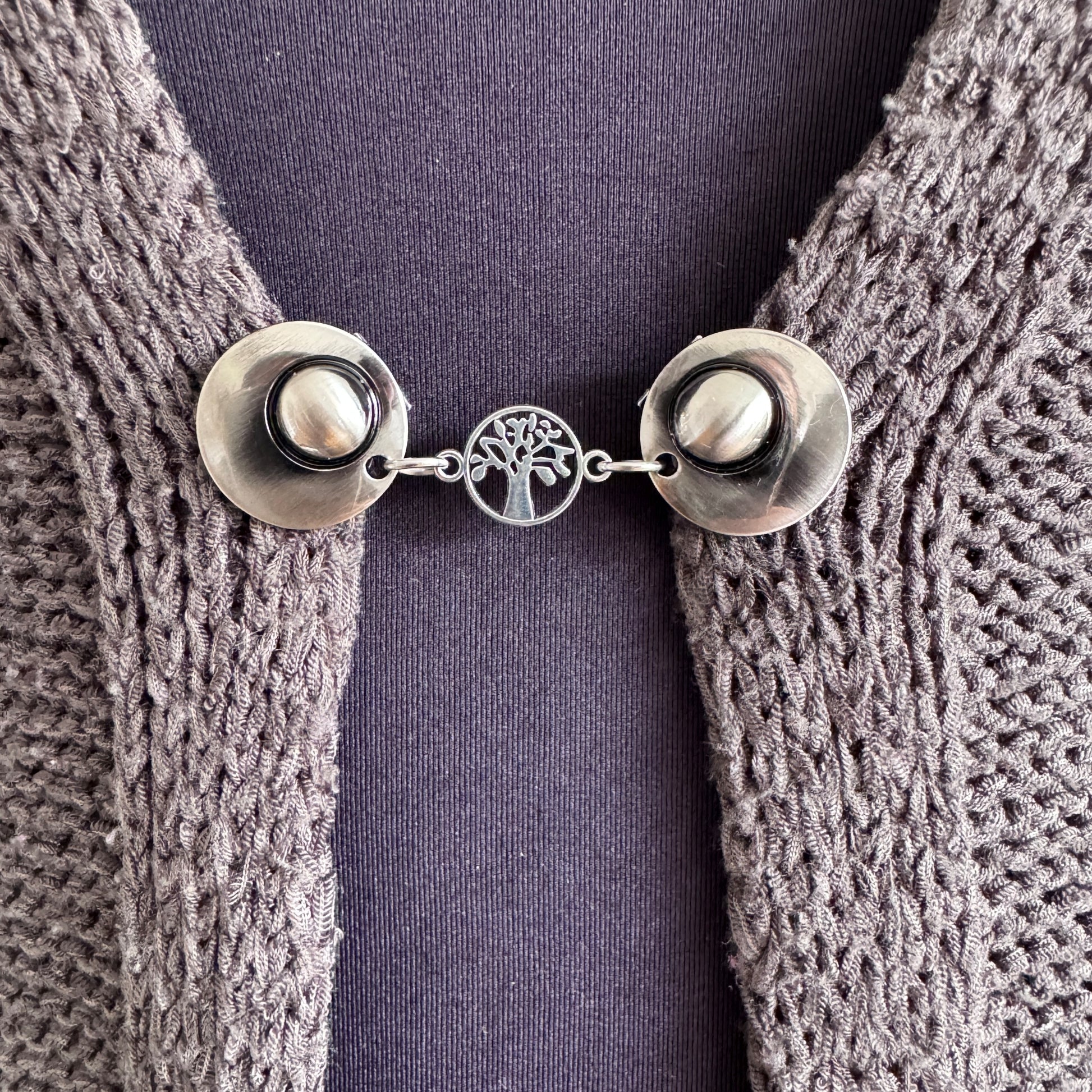 Vestsluiting De Kleine Levensboom in close-up op een gebreid vest, elegante Fashionclip met zilverkleurige clips en levensboom tussenbedel.