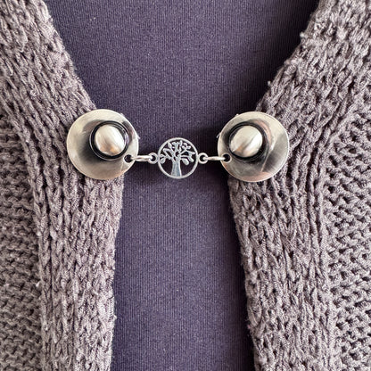 Vestsluiting De Kleine Levensboom in close-up op een gebreid vest, elegante Fashionclip met zilverkleurige clips en levensboom tussenbedel.