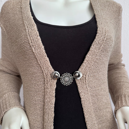 Vestsluiting De Mandala gedragen op een beige gebreid vest, elegante Fashionclip met zilverkleurige clips en opengewerkte mandala tussenbedel.