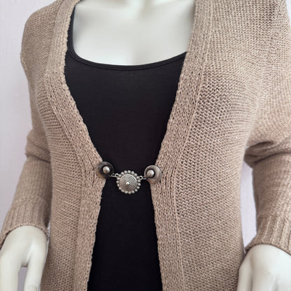 Vestsluiting De Pracht van Zeeland gedragen op een beige gebreid vest, elegante Fashionclip met zilverkleurige clips en Zeeuwse knop tussenbedel.
