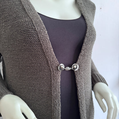 Vestsluiting Engelenvleugels gedragen op een taupekleurig gebreid vest, elegante Fashionclip met zilverkleurige clips en sierlijke vleugel tussenbedel.