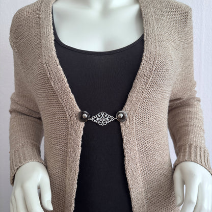 Vestsluiting Frans Brocante zilver gedragen op een beige gebreid vest, elegante Fashionclip met zilverkleurige clips en sierlijke brocante tussenbedel.