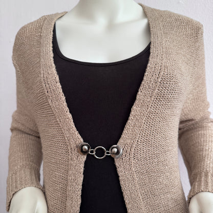 Vestsluiting Het Rondje zilver gedragen op een beige gebreid vest, elegante Fashionclip met zilverkleurige clips en ronde ringverbinding.