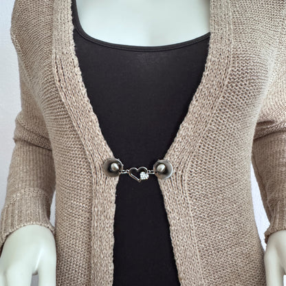 Vestsluiting Het Sprankelende Hart gedragen op een beige gebreid vest, elegante Fashionclip met zilverkleurige clips en hartvormige tussenbedel met strass.