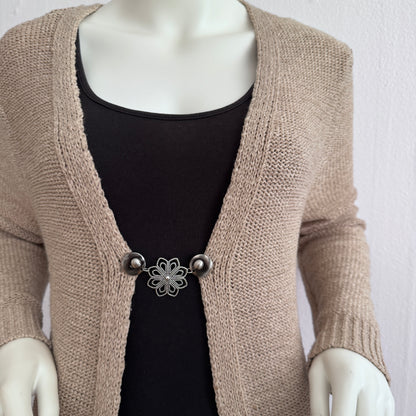 Vestsluiting IJsbloem gedragen op een beige gebreid vest, elegante Fashionclip met zilverkleurige clips en bloemvormige tussenbedel.
