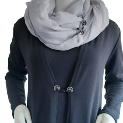 Vestsluiting Infinity zwart gedragen op een donker vest met lichte sjaal, elegante Fashionclip met zwarte clips en infinity tussenbedel.