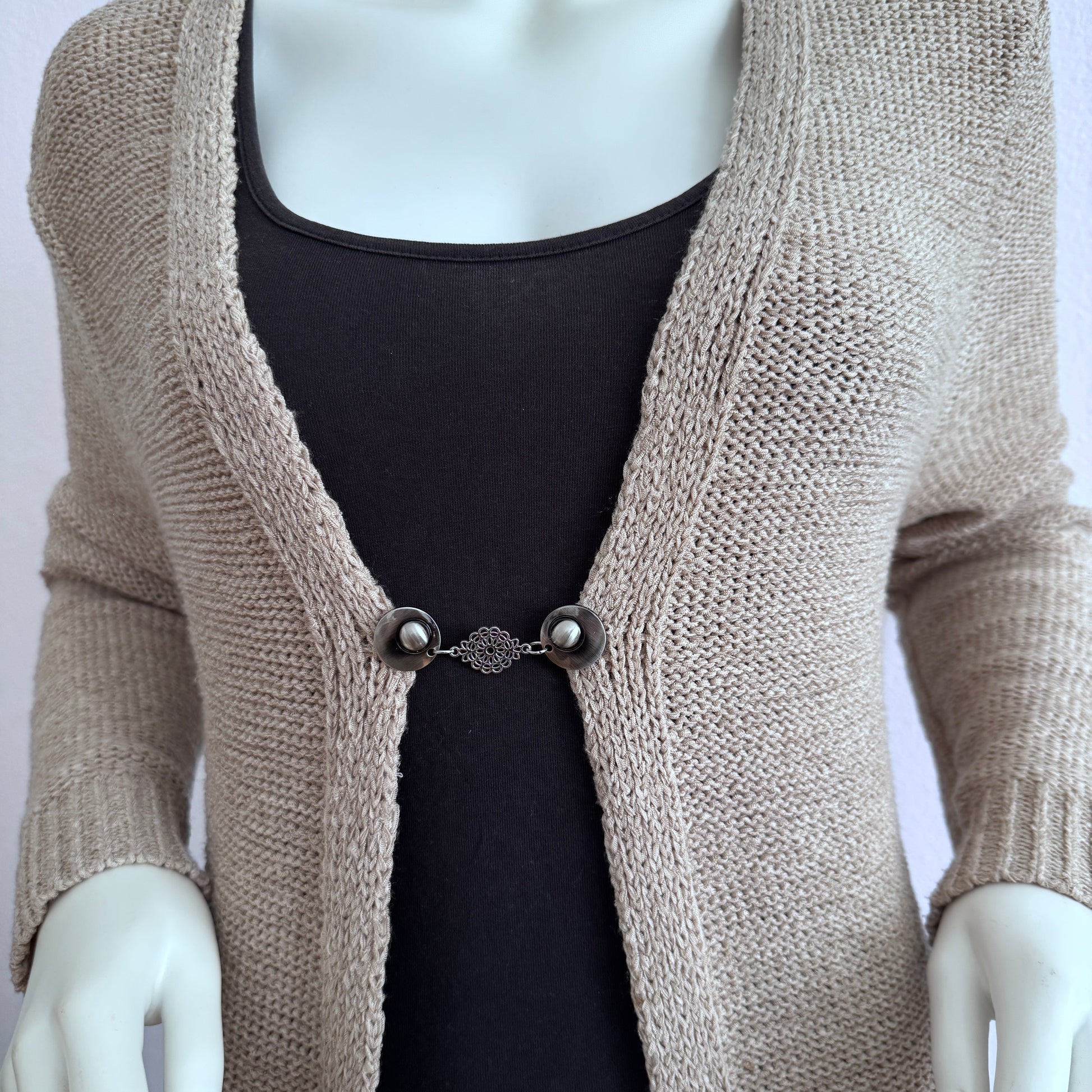 Vestsluiting Kanten Bloem gedragen op een beige gebreid vest, elegante Fashionclip met zilverkleurige clips en verfijnde bloemvormige tussenbedel.