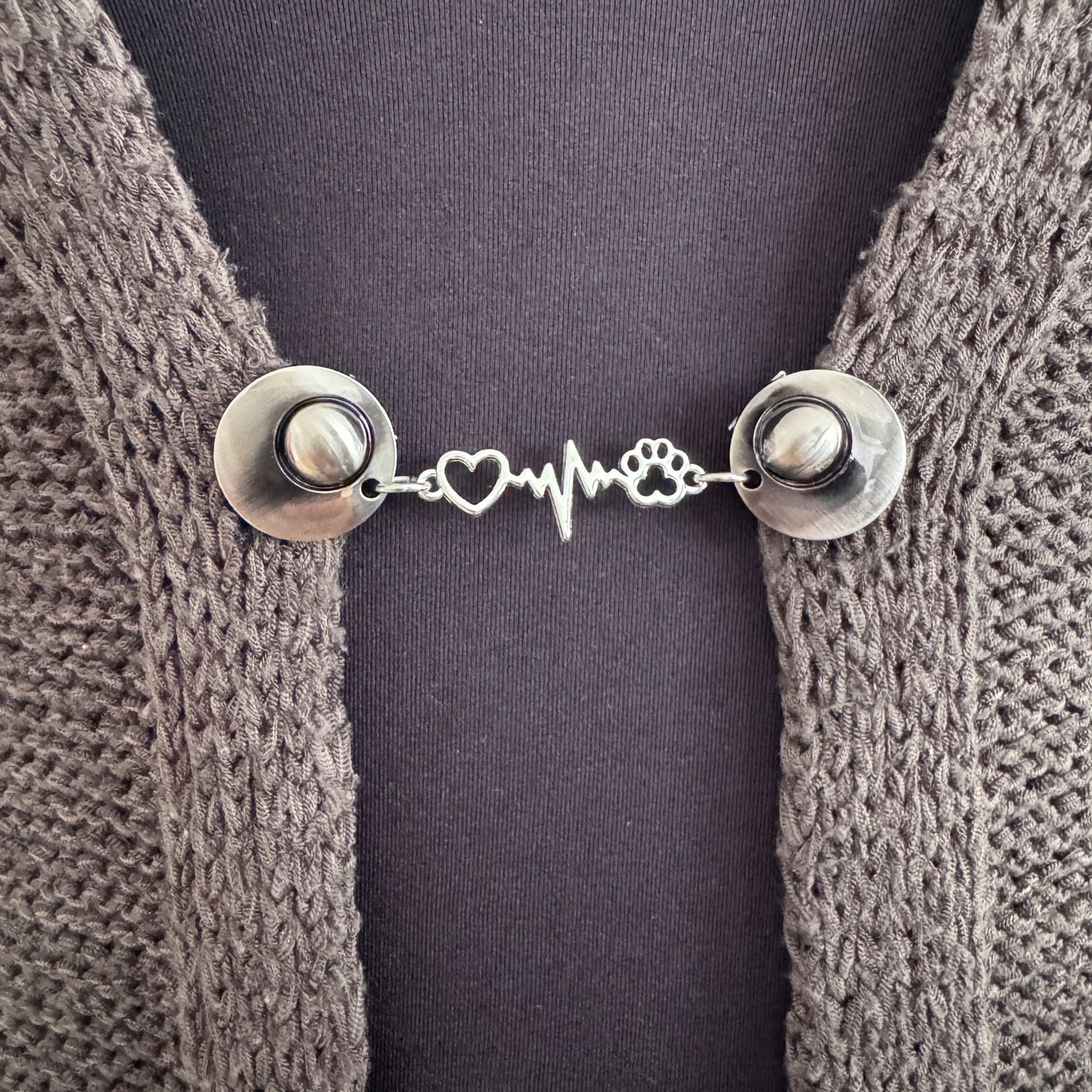 Vestsluiting Mijn Beste Vriend in close-up op een gebreid vest, elegante Fashionclip met zilverkleurige clips en hartslag tussenbedel met hondenpootje.