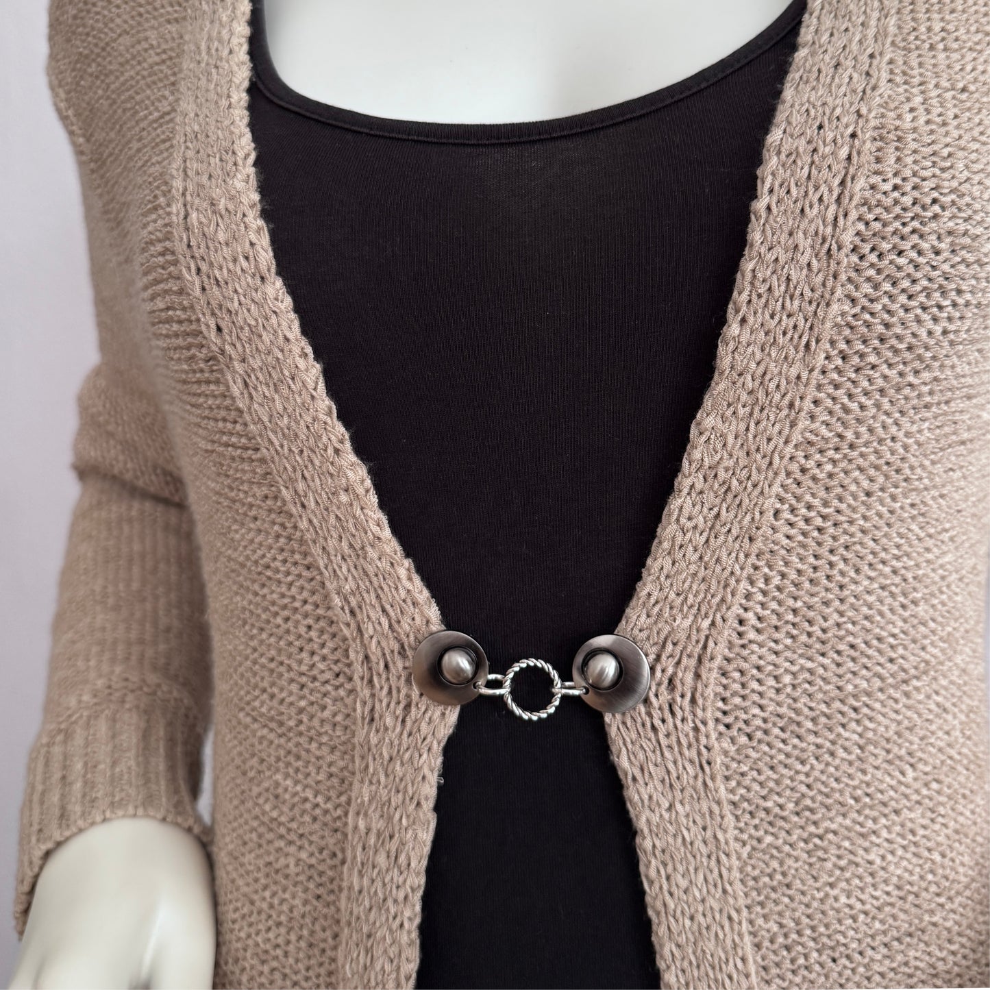 Vestsluiting Vlechtwerk met gevlochten ring, zichtbaar gedragen op een open gebreid vest met rustige uitstraling.